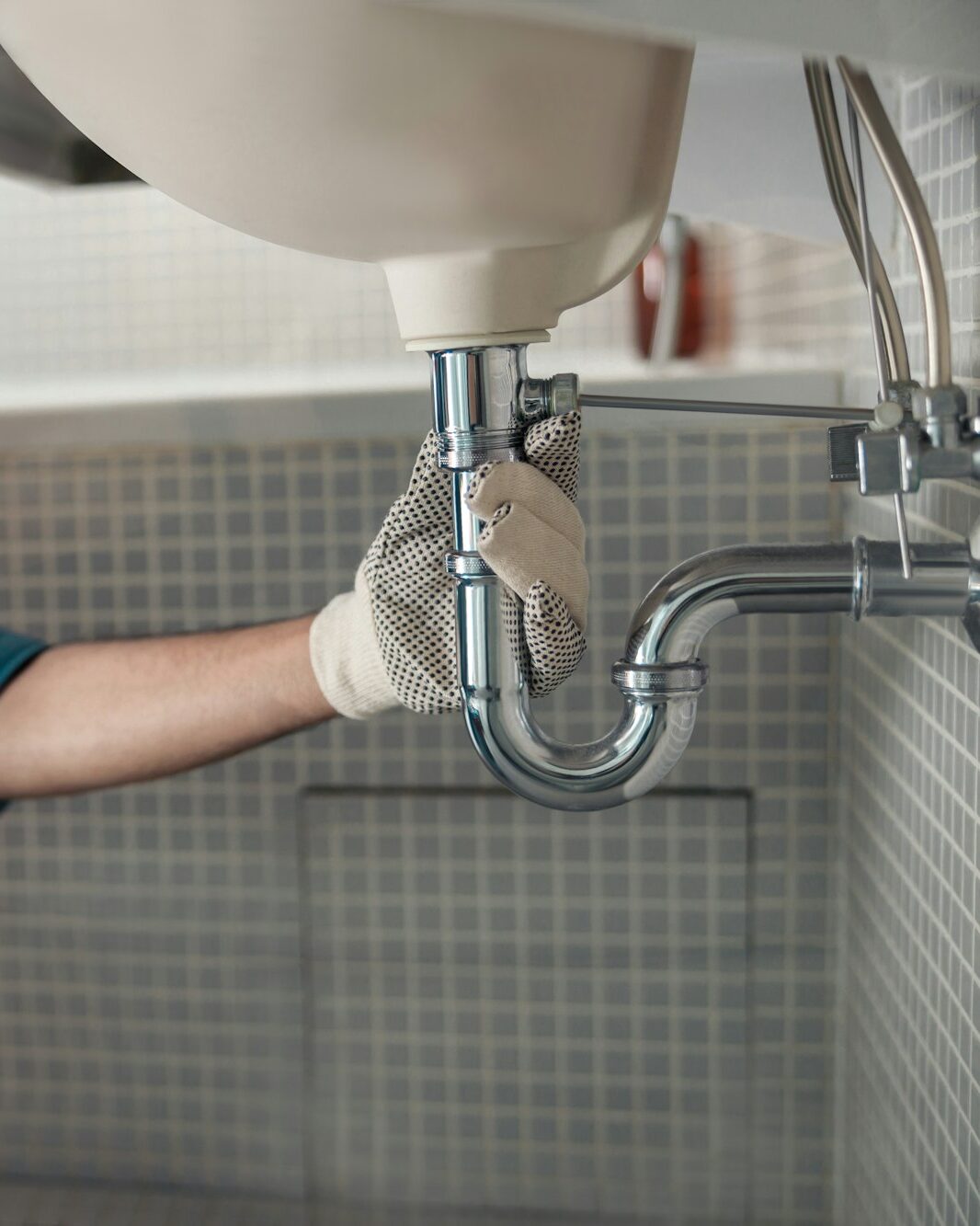Male plumber is repairing faucet of a sink at bathroom. Good quality plumbing company service